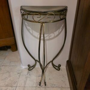 sierlijke metalen halvemaan wandtafel met sierkrullen tegen muur geplaatst