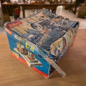 vintage Wilesco doos van stoommachine met industriële illustratie, zichtbaar beschadigd en verstevigd met tape